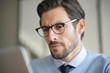 © goodluz - Portrait of attractive man working on laptop wearing glasses