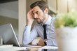 © goodluz - Stressed handsome business man looking at laptop in office