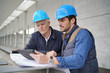 © goodluz - Workmen consulting over blueprint with tablet on modern building sight