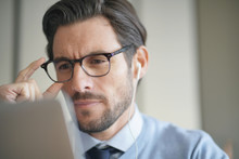 Portrait Of Attractive Man Working On Laptop Wearing Glasses