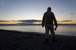 © Mint Images - A fly fisherman gets ready to wade into salt water at sunrise and fly fish for coastal cutthroat trout and salmon at a beach on the north west coastline of the USA.