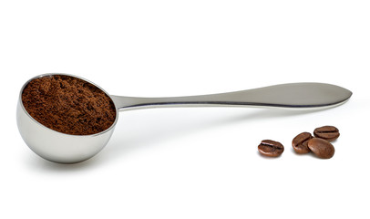 Grinded coffee powder in measuring scoop with beans isolated on white background