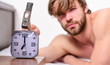 © be free - Man bearded annoyed sleepy face lay pillow near alarm clock. Guy knocking with hammer alarm clock ringing. Break discipline regime. Stop ringing. Annoying sound. Annoying ringing alarm clock