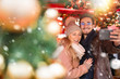 © jackfrog - A young couple do a selfie in the decorated street for Christmas