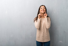 Teenager Girl With Sweater On A Vintage Wall Smiling With A Happy And Pleasant Expression