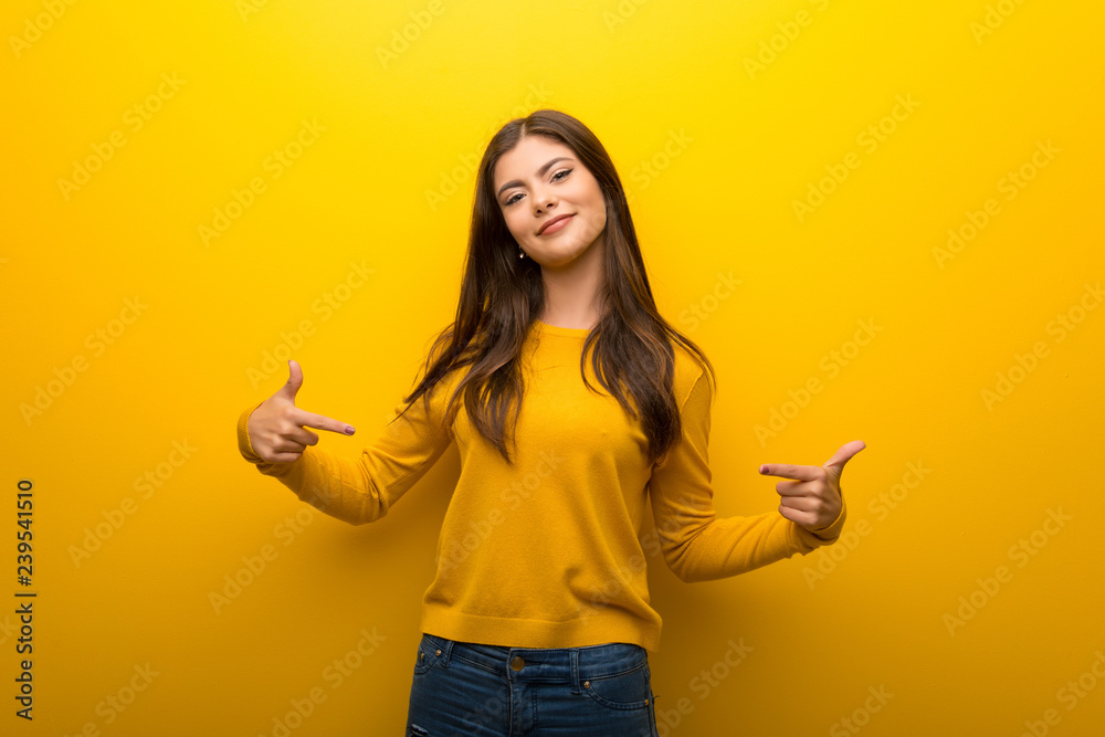 Teenager girl on vibrant yellow background proud and self-satisfied in love yourself concept - obrazy, fototapety, plakaty 