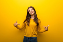 Teenager Girl On Vibrant Yellow Background Proud And Self-satisfied In Love Yourself Concept