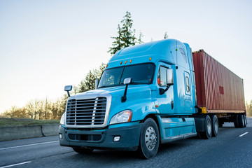 big rig long haul semi truck transporting container on the highway