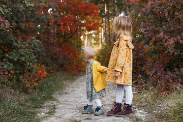 Young children walk in the autumn forest in retro dresses.