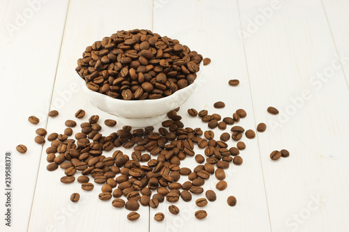 Fotografie, Obraz Roasted coffee beans in bowl on white wooden background