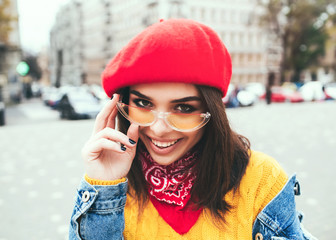 Wall Mural - Outdoors portrait of beautiful young girl laughing.Close up shot of stylish young woman in sunglasses smiling against city street background. Beautiful female model with copy space