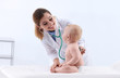 Children's doctor examining baby with stethoscope in hospital. Space for text