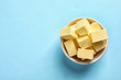 Bowl with fresh butter on color background, top view. Space for text