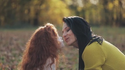 cute little girl hugging her mother in the autumn park. happy family concept