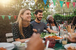 © Maskot - Smiling friends enjoying food during party in backyard