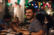 © Maskot - Portrait of smiling young man having dinner during party