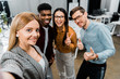© LIGHTFIELD STUDIOS - camera point of view of smiling multicultural colleagues taking selfie together in office