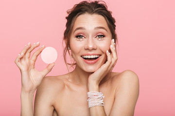 Canvas Print - Shocked happy young woman posing isolated over pink wall background holding cotton disk.