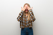 © luismolinero - Blonde young girl over white wall covering eyes by hands. Surprised to see what is ahead