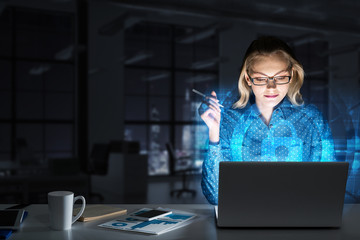 Beautiful blonde in dark office working on laptop and getting net access