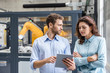 © Westend61 - Colleagues in high tech company controlling industrial robots, using digital tablet