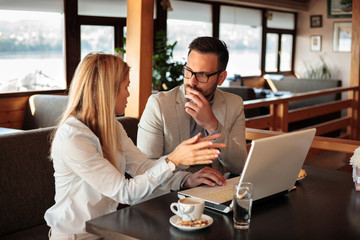 Two young male and female business partners having a meeting in a restaurant. Discussing and planning.