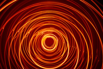 A beautiful, bright light swirl of red color. Futuristic light painting on a black background. Round light circles