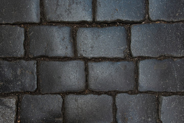 Smooth dark brick road in ancient European city. Closeup view from above.