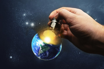Poster - Image of human hand holding light bulb with earth planet inside and sunshine. 