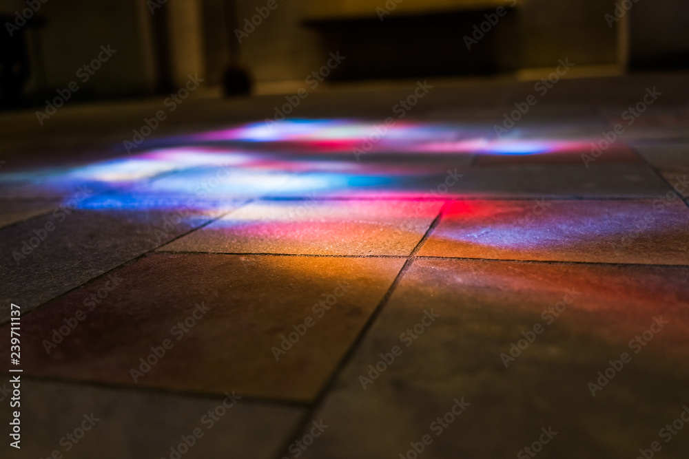 Colorful reflections of stained glass murals on stone ground low angle ...