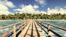 The Camera Flies Over A Wooden Bridge On A Tropical Island With An Exotic White Beach. Green Palm Trees, Blue Sky And Sun