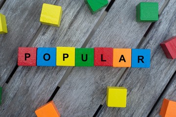 colored wooden cubes with letters. the word popular is displayed, abstract illustration