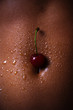 © Tverdokhlib - The belly of a dark-skinned woman with cherries and drops of water. Sexy girl closeup. African American pretty girl. Cherry for dessert. Erotic concept.