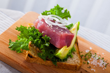 Wall Mural - Tasty sandwich with raw tuna, avocado and greens  at plate