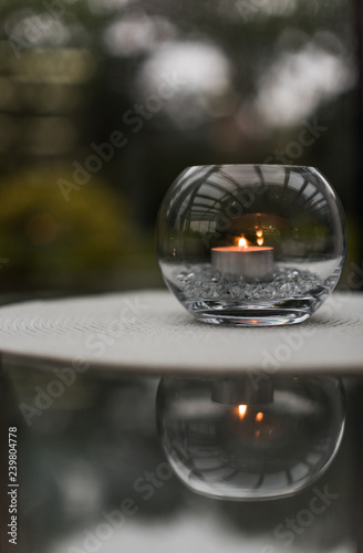A Decorative Glass Bowl With A Candle And Filler Inside Standing