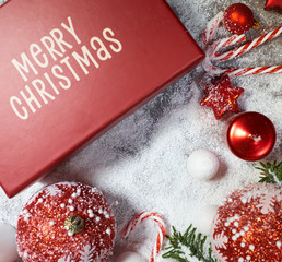 Christmas gift box, candy cane and fir tree branch on snow table