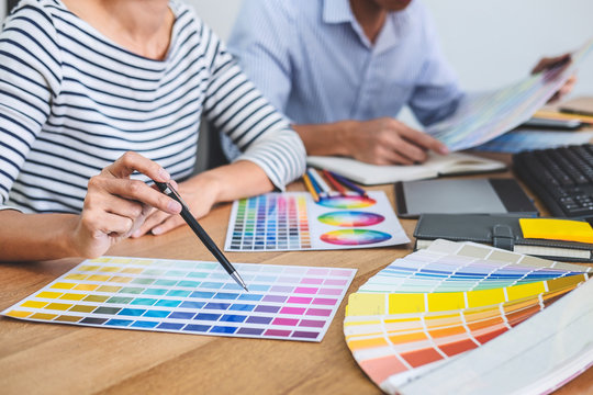 Two colleagues creative graphic designer working on color selection and drawing on graphics tablet at workplace, Color swatch samples chart for selection coloring