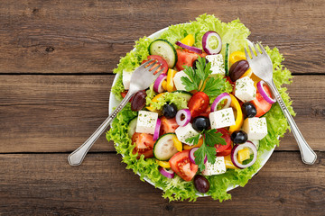 Wall Mural - Greek salad with feta cheese, organic black olives, juicy tomatoes, red pepper, red onion, cucumber and lettuce.