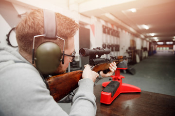 Shooting training. Man shoots from aim gun in paper target