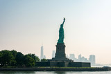 Fototapeta Nowy Jork - Liberty statue in New York City with skyline of the island of Manhattan