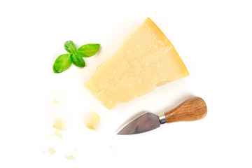 Wall Mural - A piece of aged Parmesan cheese with crumbs, shot from the top on a white background with fresh basil leaves, a cheese knife, and copy space