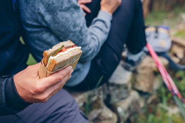 Detail of a sandwich that a couple is going to eat making a break to do trekking