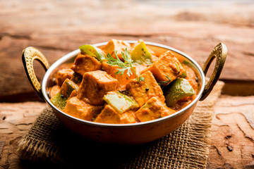 Wall Mural - Malai or achari Paneer in a gravy made using red gravy and green capsicum. served in a bowl. selective focus