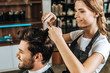 © LIGHTFIELD STUDIOS - smiling young hairdresser cutting hair to handsome happy man in beauty salon