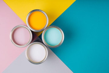 four open cans of paint on bright symmetry background. yellow, white, pink, turquoise colors of pain