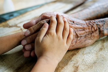 Hands of the old man and a child's hand on the wood table