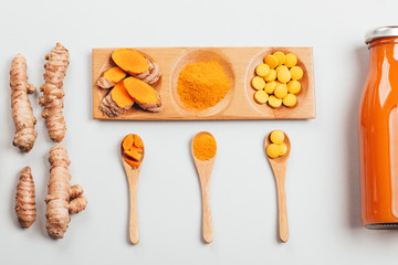 Wall Mural - Turmeric in different conditions: fresh in bottle, pills, powder and cut plant on wooden tray. Flat lay style.