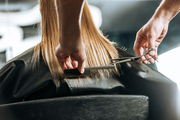 Hairdresser cutting hair to beautiful young woman in beauty salon