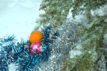 New Year's background with a branch of a Christmas tree, toys and tangerine on the snow