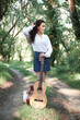© soleg - young woman walking in the forest and playing guitar, summer nature, bright sunlight, shadows and green leaves, romantic feelings